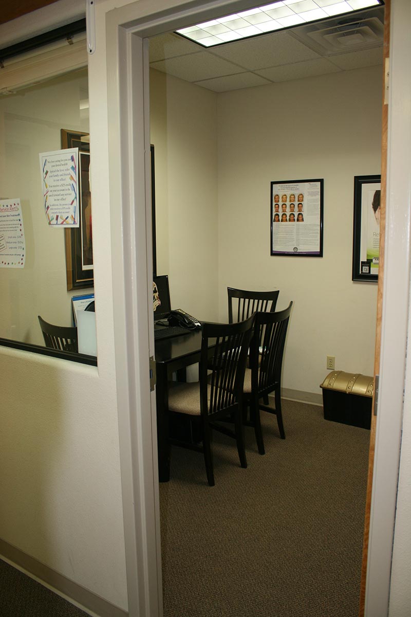 The image shows an interior view of an office space with a door open, revealing a meeting room with chairs and tables inside.