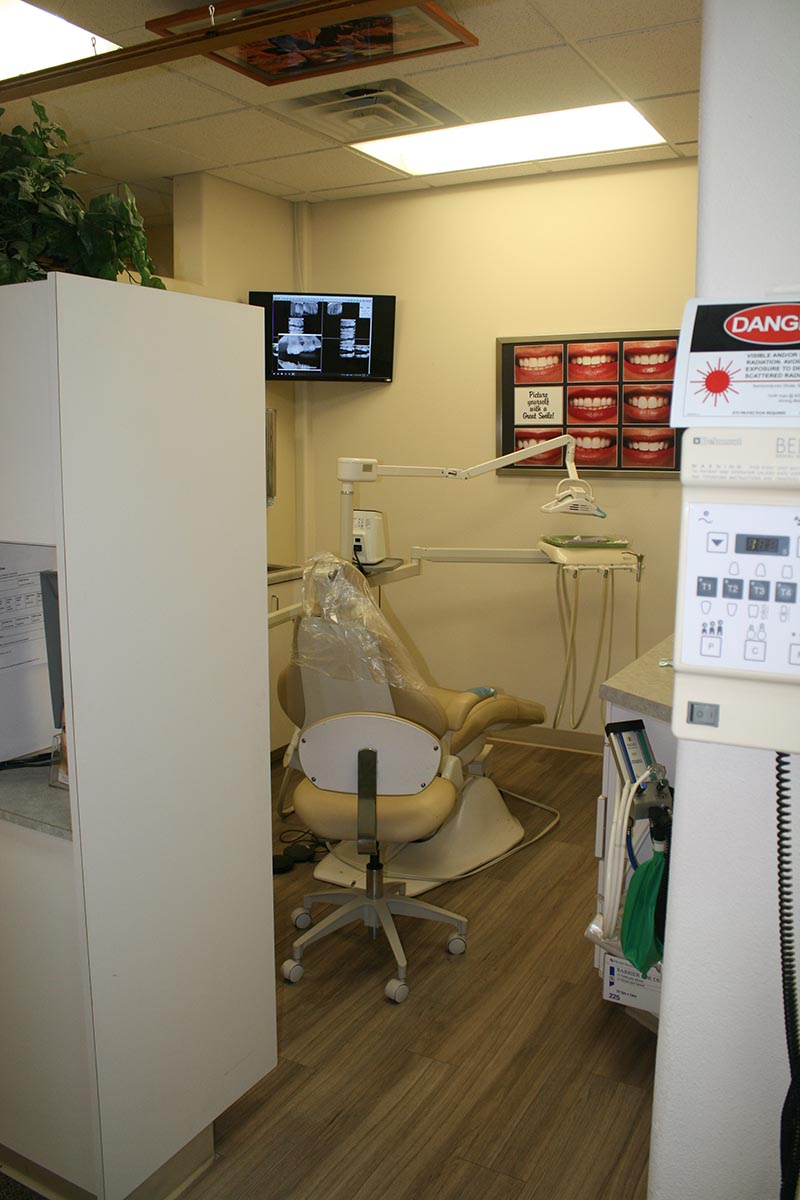 The image shows an interior view of a dental office with chairs, equipment, and a waiting area.