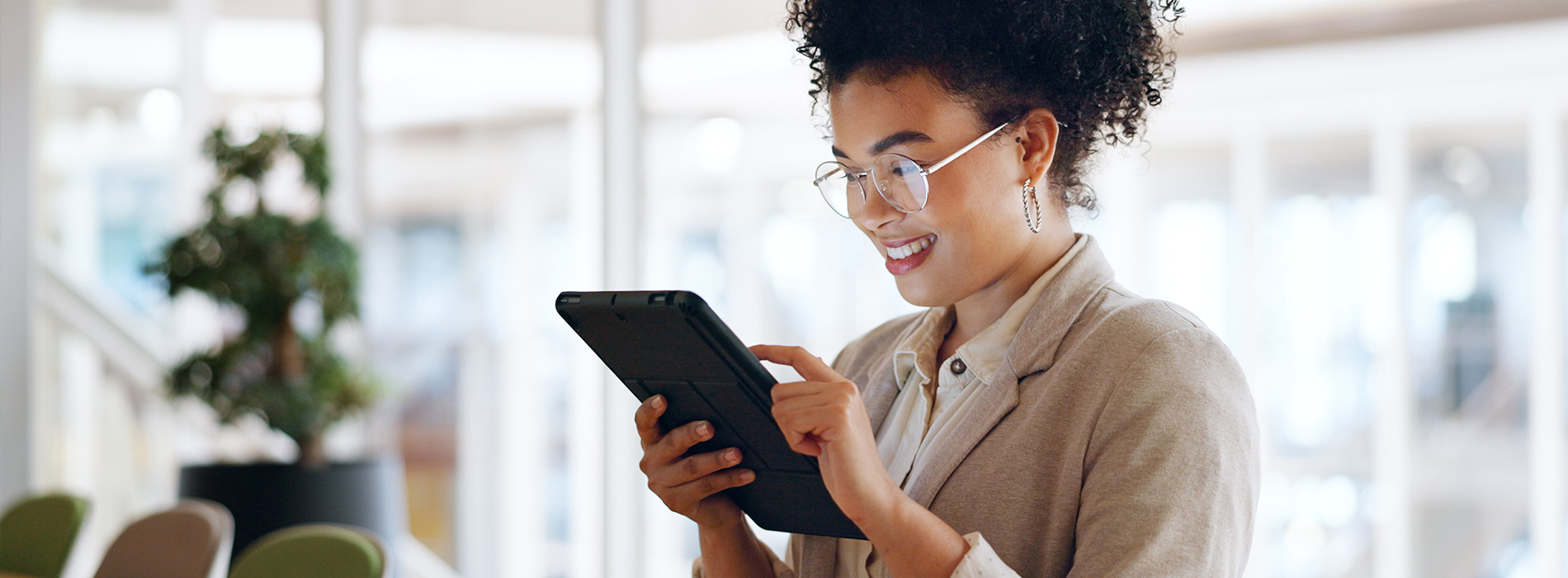 A person holding a tablet with both hands while standing in a brightly lit indoor space.