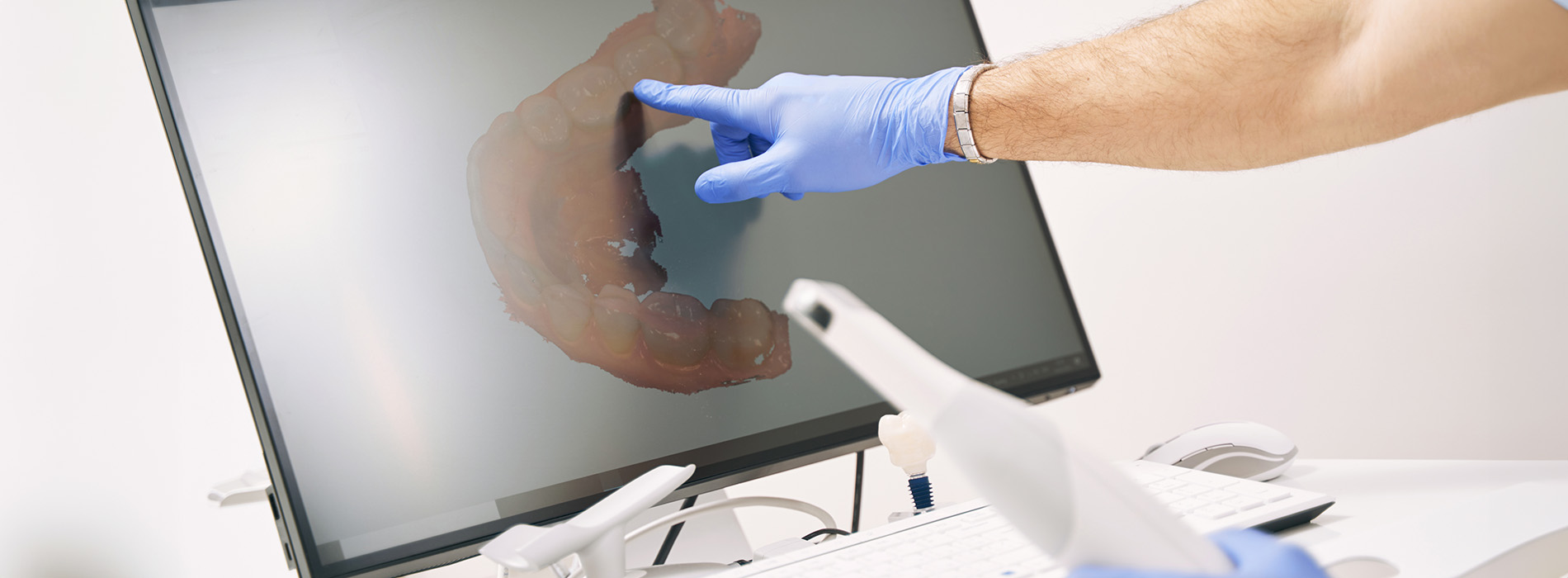 The image shows a person wearing blue gloves holding a large fish with their left hand while standing in front of a computer monitor.
