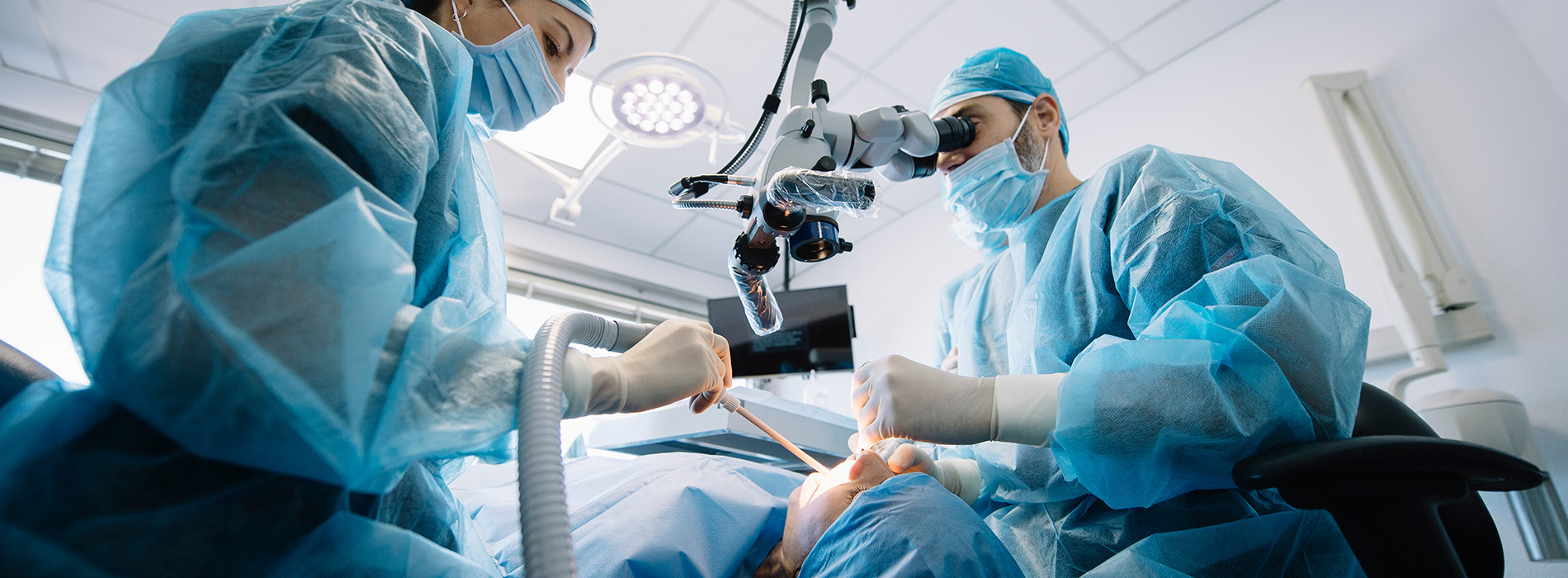 Two surgeons performing surgery with surgical equipment and instruments around them in an operating room.