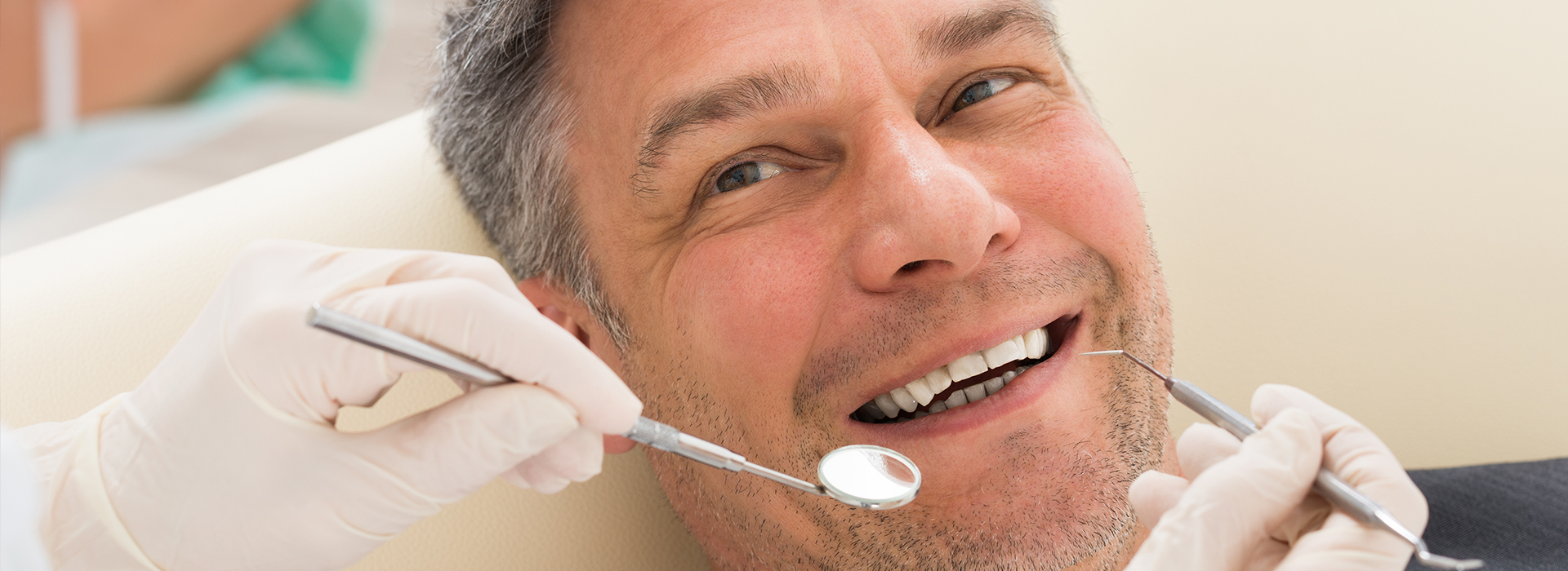 A man wearing a surgical mask and holding dental tools near his face.