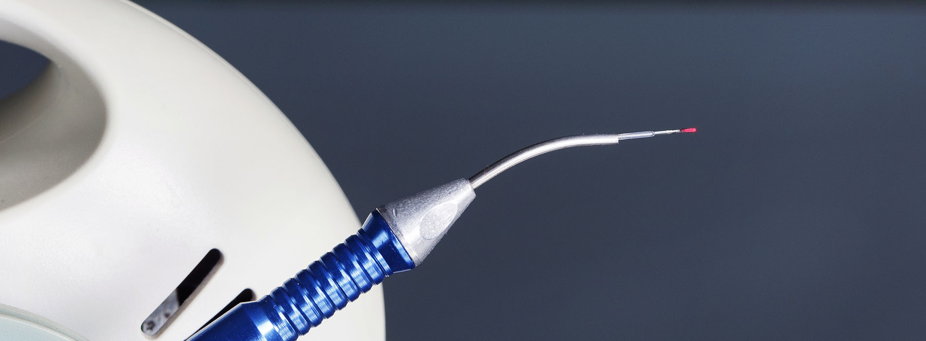 The image shows a close-up of a blue toothbrush with bristles against a blurred background.