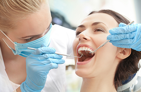 A dental hygienist performing a teeth cleaning procedure on a patient s mouth using specialized dental tools.