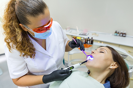 A dental hygienist is using an ultrasonic scaler on a patient s teeth during a dental cleaning procedure.