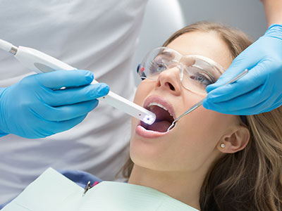 A woman receiving dental care  she s seated with a dental device inserted into her mouth while being attended to by healthcare professionals using specialized equipment.