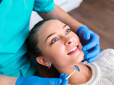 A woman receiving dental care while smiling at the camera.