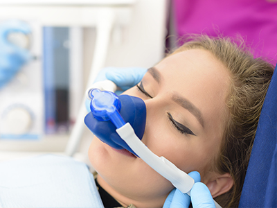 Woman receiving oxygen therapy while lying down with medical equipment around her face.